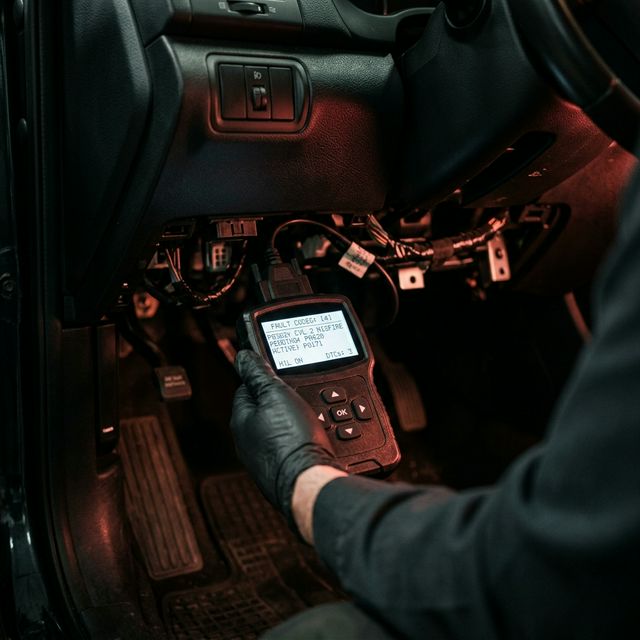 OBD diagnostic scanner reading fault codes under dashboard